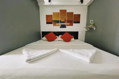 a bed with white sheets and red pillows on it at Casa Picasso Near Chabad House in Bangkok