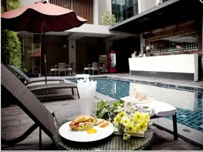 a table with a plate of food next to a pool at Siam Swana in Bangkok