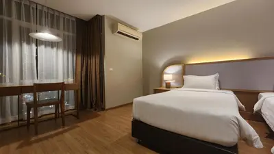 a hotel room with a bed and a desk and a window at Brighton Hotel Bangkok in Bangna