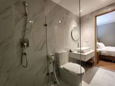 a bathroom with a shower and a toilet and a sink at Brighton Hotel Bangkok in Bangna
