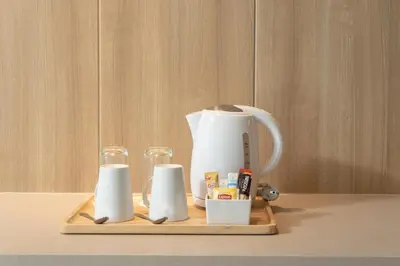 a tea kettle and three cups on a wooden tray at VIC 3 Bangkok Hotel in Bangkok