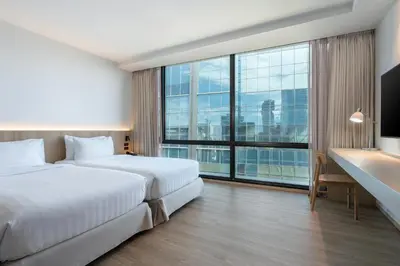 a hotel room with a bed and a desk and a large window at VIC 3 Bangkok Hotel in Bangkok