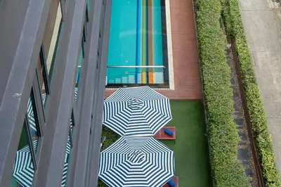 a white and black umbrella on a floor next to a swimming pool at VIC 3 Bangkok Hotel in Bangkok