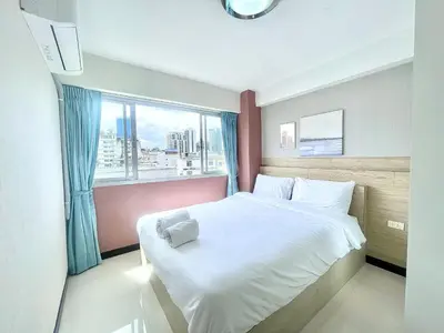 a bedroom with a white bed and a window at Baan Sabai Rama IV Apartment in Bangkok