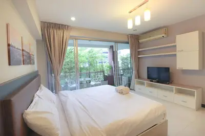 a bedroom with a bed and a tv and a window at Baan Sabai Rama IV Apartment in Bangkok