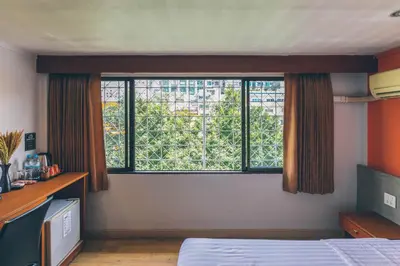 a bedroom with a bed and a large window at Atlas Bangkok Hotel in Bangkok