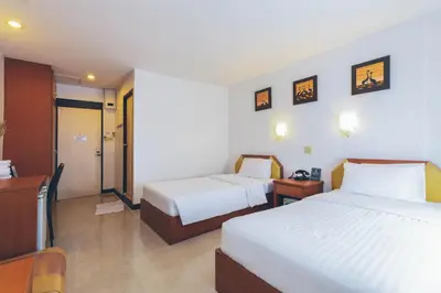 a hotel room with two beds and a desk at Atlas Bangkok Hotel in Bangkok