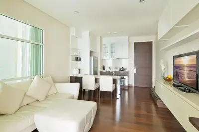 a living room with a white couch and a kitchen at Ivy Thonglor 55 in Bangkok