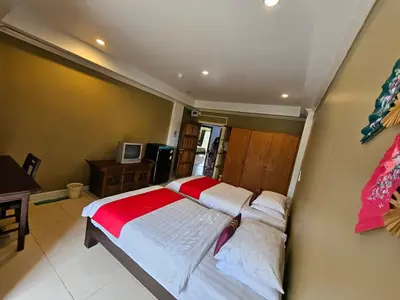 a bedroom with two beds and a desk and a television at Royal Pimand Hotel in Bangkok
