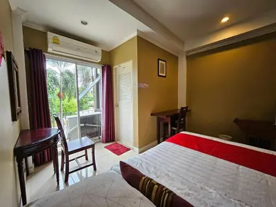 a bedroom with a bed and a desk and a window at Royal Pimand Hotel in Bangkok