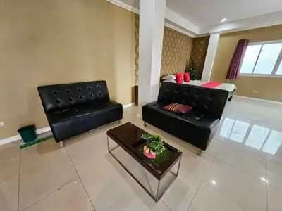 a living room with a black leather couch and a table at Royal Pimand Hotel in Bangkok