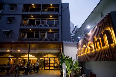 a building with people sitting outside of it at night at Maxim's Inn in Bangkok