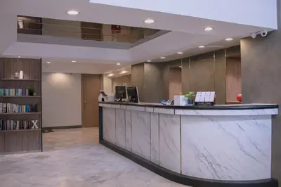 a lobby with a counter and a book shelf at Maxim's Inn in Bangkok