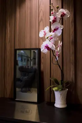 a flower in a vase on a table next to a picture at Maxim's Inn in Bangkok