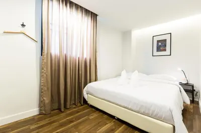 a white bedroom with a bed and a window at Metro hotel in Bangkok