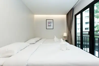 a white bedroom with a large bed and a large window at Metro hotel in Bangkok