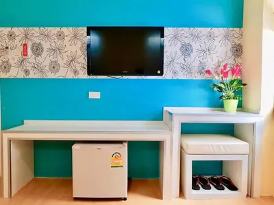a desk with a tv on a blue wall at The Konnect Hotel in Bangkok