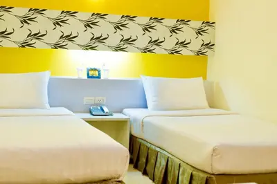 two beds in a room with yellow walls at The Konnect Hotel in Bangkok