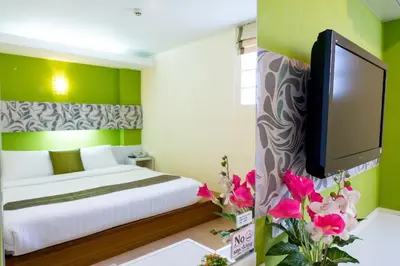 a bedroom with a bed and a tv and flowers at The Konnect Hotel in Bangkok