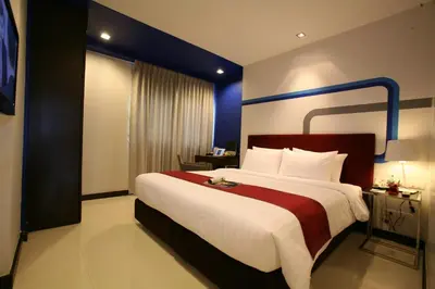 a bedroom with a large bed with a red and white blanket at FX Hotel Metrolink Makkasan in Bangkok