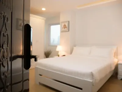 a white bedroom with a white bed and a window at The Kinn Bangkok in Bangkok