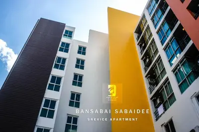 a building with a yellow sign in front of it at Bansabai Sabaidee Service Apartment in Bangkok