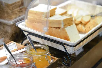 a tray of cheese and a jar of honey and a tray of bread at Chillax Heritage Hotel Khaosan in Bangkok