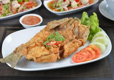 a plate of food with fish and vegetables on a table at Chillax Heritage Hotel Khaosan in Bangkok