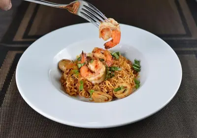 a plate of shrimp and noodles with a fork at Chillax Heritage Hotel Khaosan in Bangkok