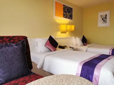 a hotel room with three beds and a chair at Tongtara Riverview Hotel in Bangkok
