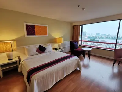 a hotel room with a bed and a large window at Tongtara Riverview Hotel in Bangkok