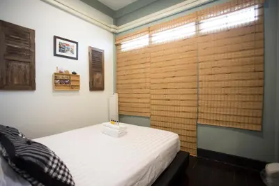 a bedroom with a bed and a large window at The Orientale Hostel in Bangkok