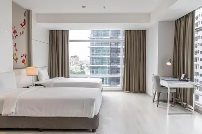 a hotel room with two beds and a desk at Jasmine 59 Hotel in Bangkok