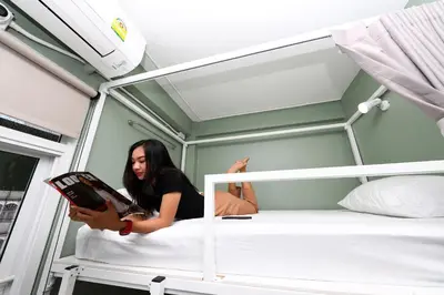 a woman is reading a book in a bunk bed at Ekanake hostel in Bangkok