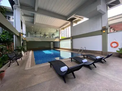 a swimming pool in a building with chairs around it at Boss Hotel in Bangkok