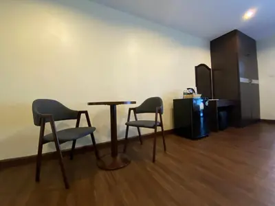 a room with two chairs and a table and a refrigerator at Boss Hotel in Bangkok