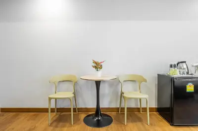 a table with three chairs and a table with a plant on it at Boss Hotel in Bangkok