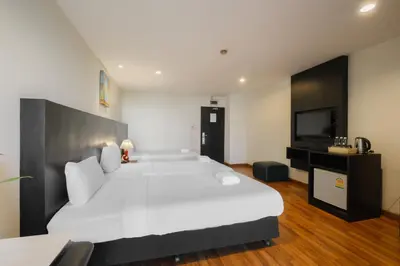 a bedroom with a large white bed and a tv at Boss Hotel in Bangkok