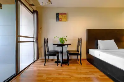 a bedroom with a bed and a table and chairs at Boss Hotel in Bangkok