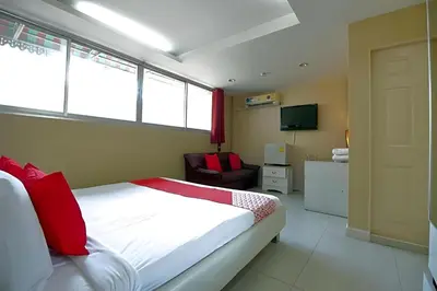 a bedroom with a bed and a chair and a television at Diamond Residence Silom in Bangkok