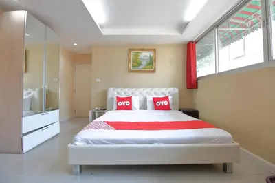 a bedroom with a white bed with two red pillows at Diamond Residence Silom in Bangkok