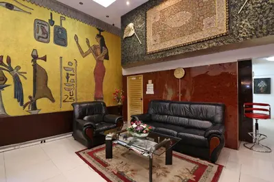 a living room with black leather furniture and a mural at Diamond Residence Silom in Bangkok