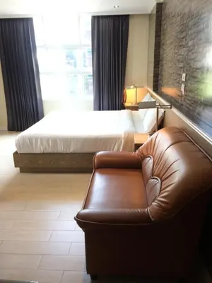 a hotel room with a bed and a leather couch at Bourbon St. Boutique Hotel in Bangkok