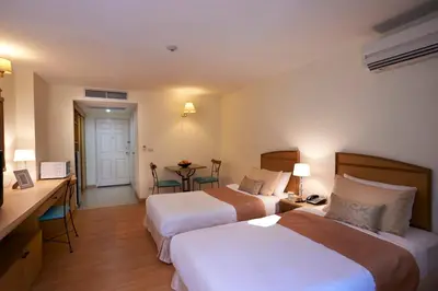 a hotel room with two beds and a desk at Ravipha Residences in Bangkok