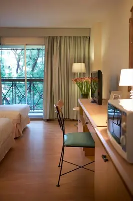 a hotel room with a desk with a television and a bed at Ravipha Residences in Bangkok
