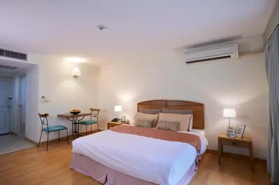 a bedroom with a bed and a table with chairs at Ravipha Residences in Bangkok
