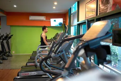 a man in a gym with rows of exercise bikes at Ravipha Residences in Bangkok