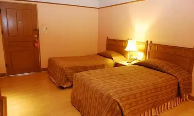 a hotel room with two beds and a lamp at Silom Village Inn in Bangkok
