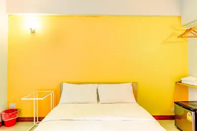 a bed in a room with a yellow wall at Living Naraa Place in Bangkok