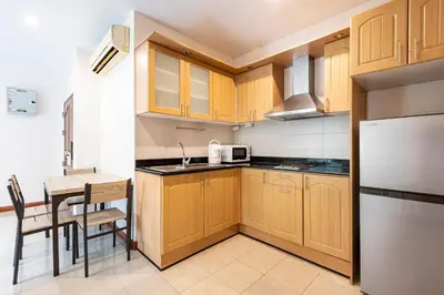 a small kitchen with wooden cabinets and a table at Teja Hotel in Bangkok